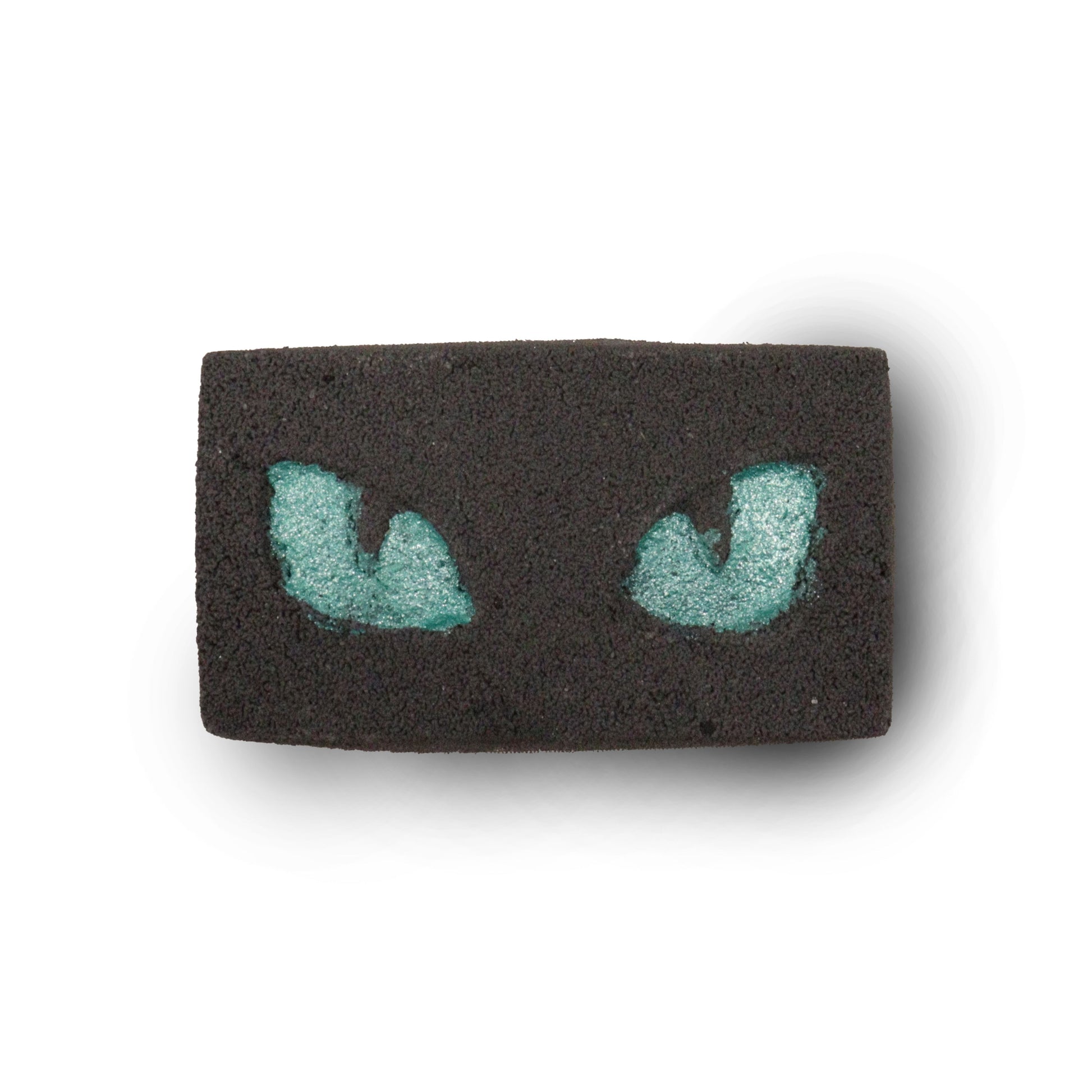 A dark, charcoal-grey bath bomb featuring two glowing-style green cat eyes, creating a mysterious and fun bath experience.