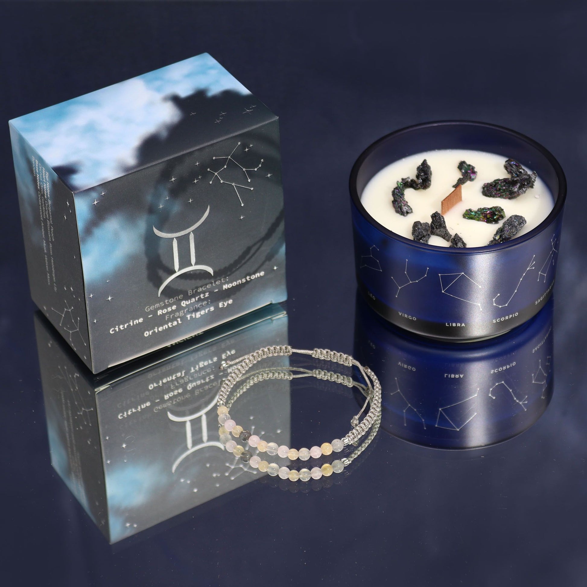 A sophisticated dark candle tin featuring Gemini twins illustrations and a surprise gemstone bead bracelet.