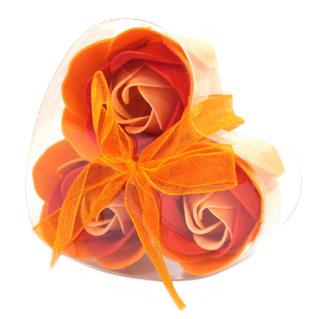 A small heart-shaped gift box containing three realistic peach-colored soap rose flowers.