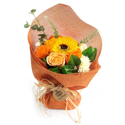 A standing bouquet of bright orange soap flowers wrapped in decorative orange and yellow paper with a ribbon.