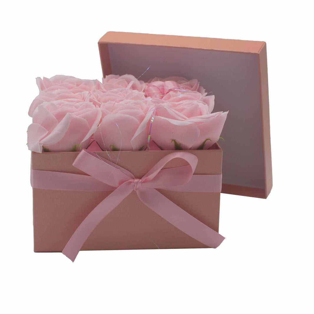 An elegant square gift box containing 9 realistic pink soap rose flowers for a luxury bath soak.