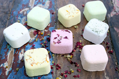A small gift box displaying colorful heart and square-shaped shower steamers infused with therapeutic essential oils.