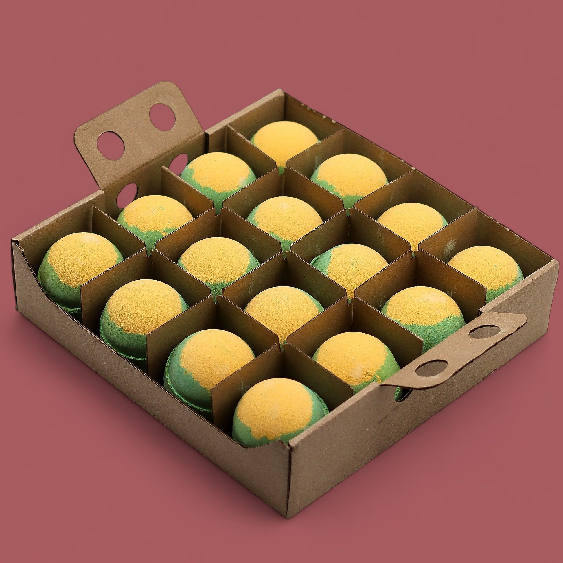 A bulk wooden tray containing sixteen large, pale yellow apple and custard scented bath bombs in a neat arrangement.