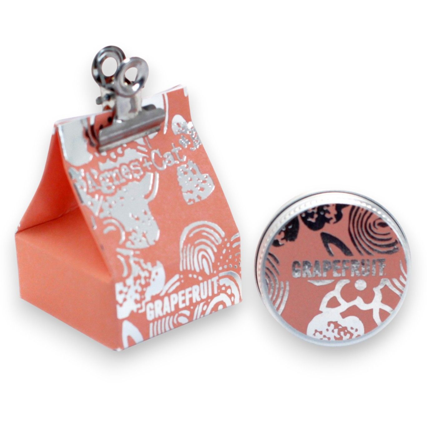 A 20g round tin of grapefruit-scented lip balm shown with its bright orange-themed gift packaging.