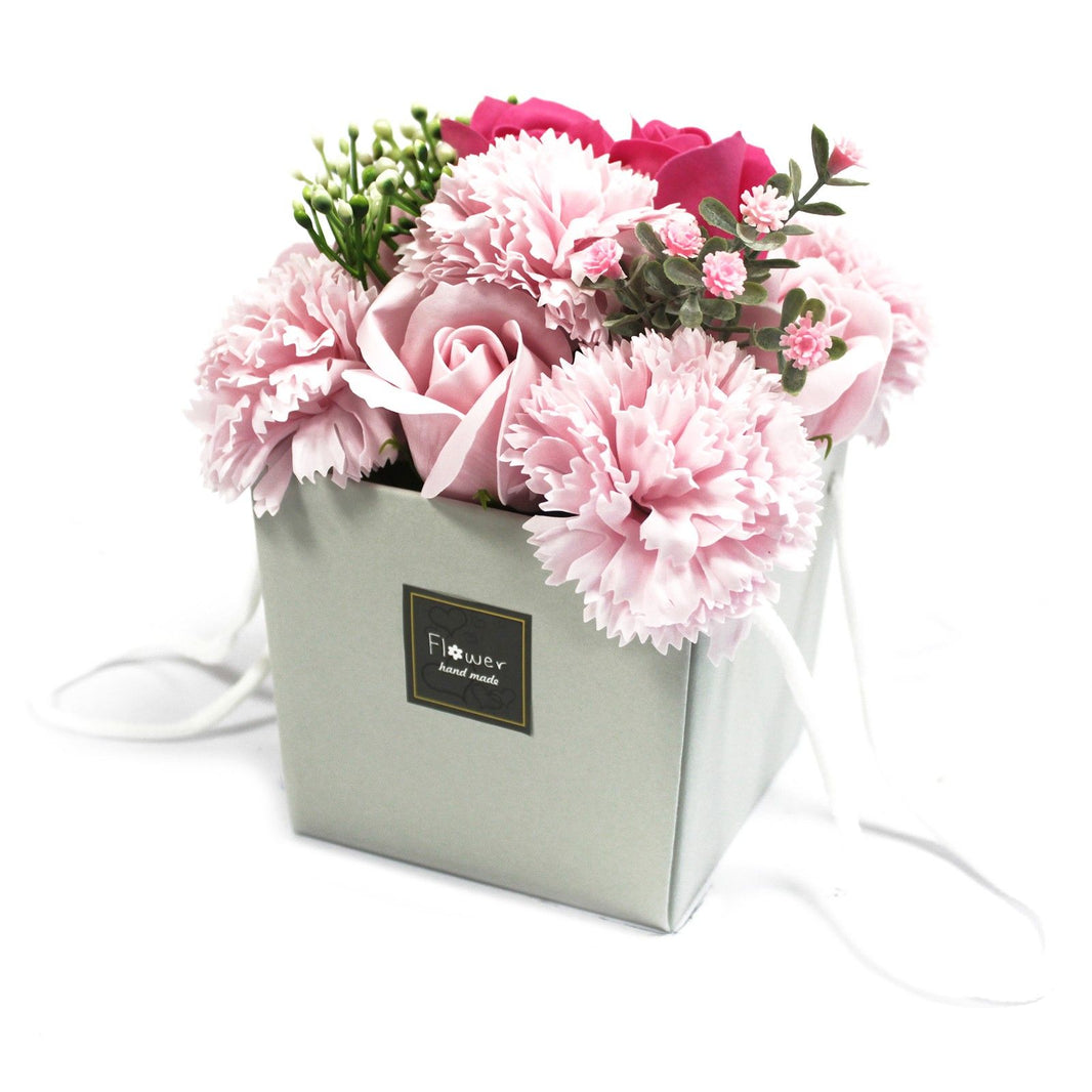 A luxury soap flower bouquet with light pink roses and carnations arranged in a square cream-colored gift box.