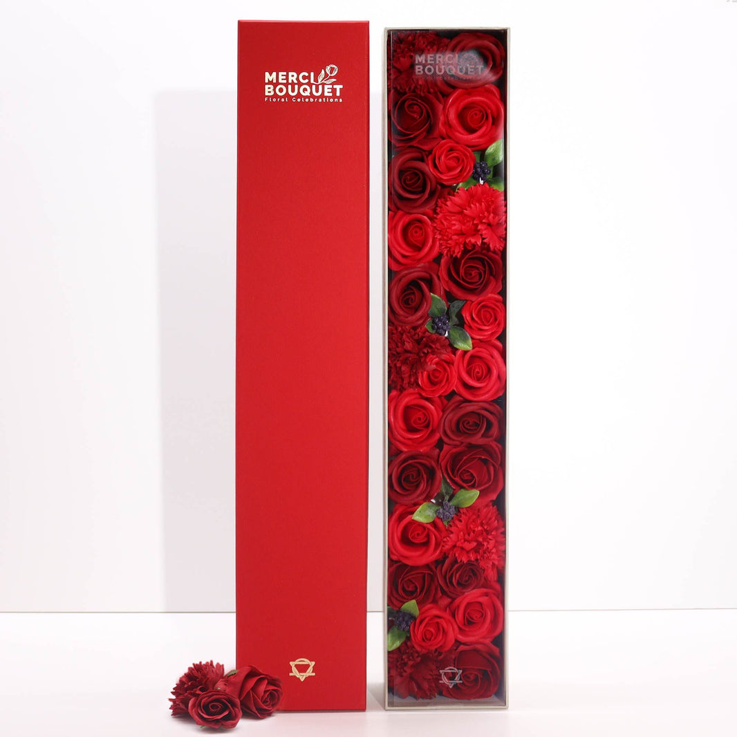 A tall, slender red gift box decorated with classic rose illustrations, containing rose-scented bath salts and soaps.