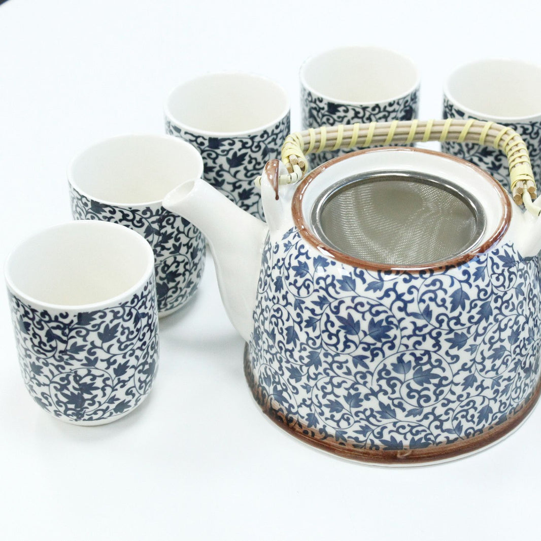 A traditional white ceramic teapot and matching handleless cups featuring a detailed deep blue floral and geometric pattern.