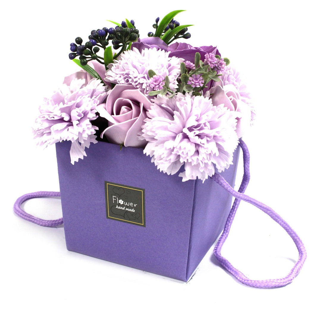 A purple and pink soap flower bouquet with lavender, roses, and carnations in a decorative purple gift box.