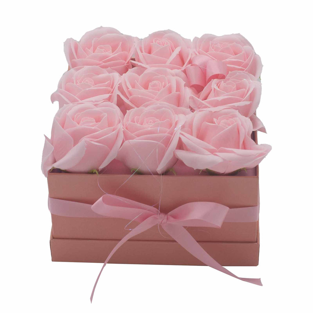 An elegant square gift box containing 9 realistic pink soap rose flowers for a luxury bath soak.