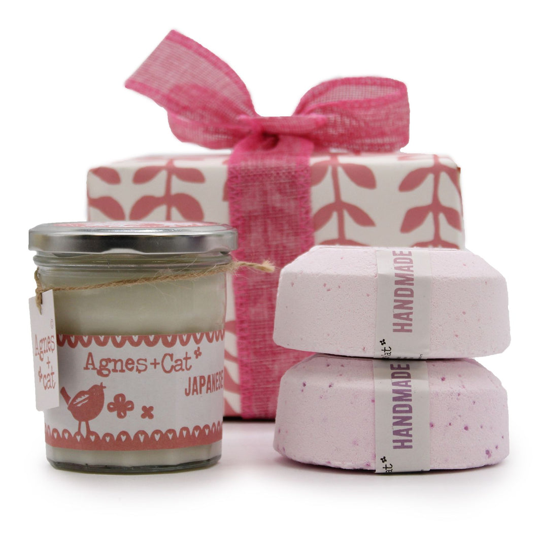 A beautiful pink-themed gift set featuring a tin candle, bath fizzers, and a small flower guest soap tied with a pink ribbon.