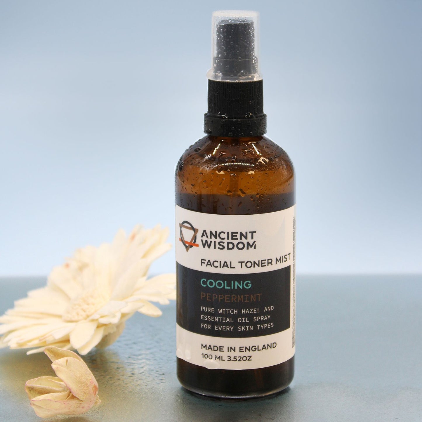 A 100ml amber glass spray bottle of Witch Hazel infused with Peppermint, featuring a professional apothecary-style label.