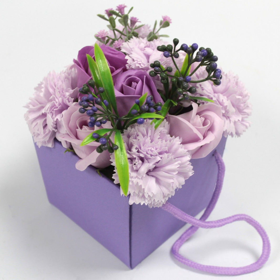 A purple and pink soap flower bouquet with lavender, roses, and carnations in a decorative purple gift box.