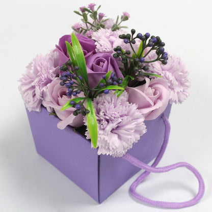 A purple and pink soap flower bouquet with lavender, roses, and carnations in a decorative purple gift box.