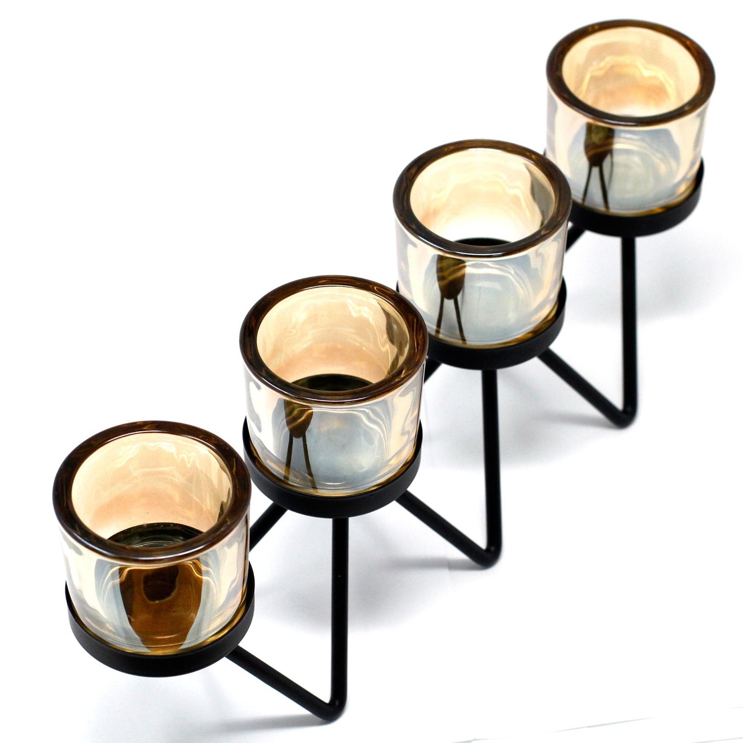 A modern black iron candle holder featuring a zigzagging metal frame that supports four separate clear glass votive cups.