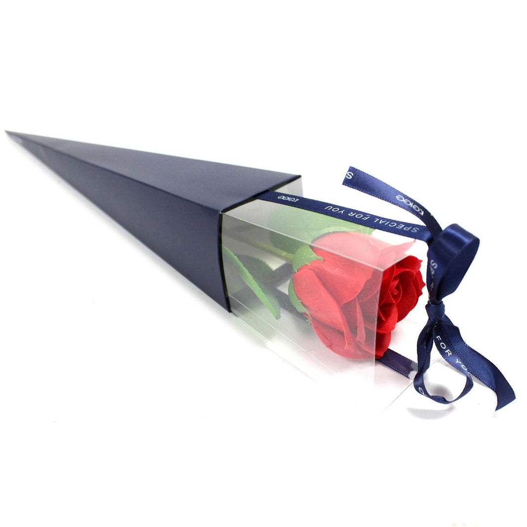 A single classic red soap flower rose in a transparent triangular gift box with a decorative ribbon.