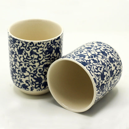 A pair of handleless ceramic tea cups featuring a deep blue and white traditional floral and geometric pattern.