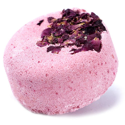 A soft pink bath bomb generously topped with a layer of dried red rose petals for a premium bath experience.