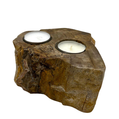 A heavy, polished double candle holder made from natural petrified wood with two holes for tealight candles.