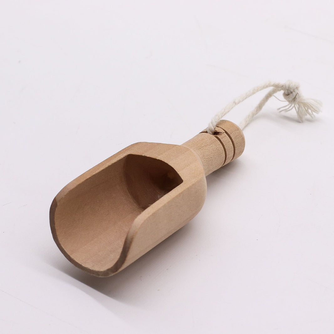 A small, handcrafted natural wooden scoop, perfect for measuring bath salts, tea, or apothecary powders.