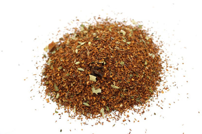 A high-volume pile of red rooibos tea leaves blended with digestive-friendly herbs and seeds.