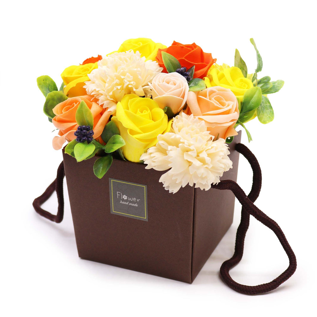 A vibrant arrangement of yellow, orange, and white soap flowers in a gift box, looking like a real Spring floral bouquet.