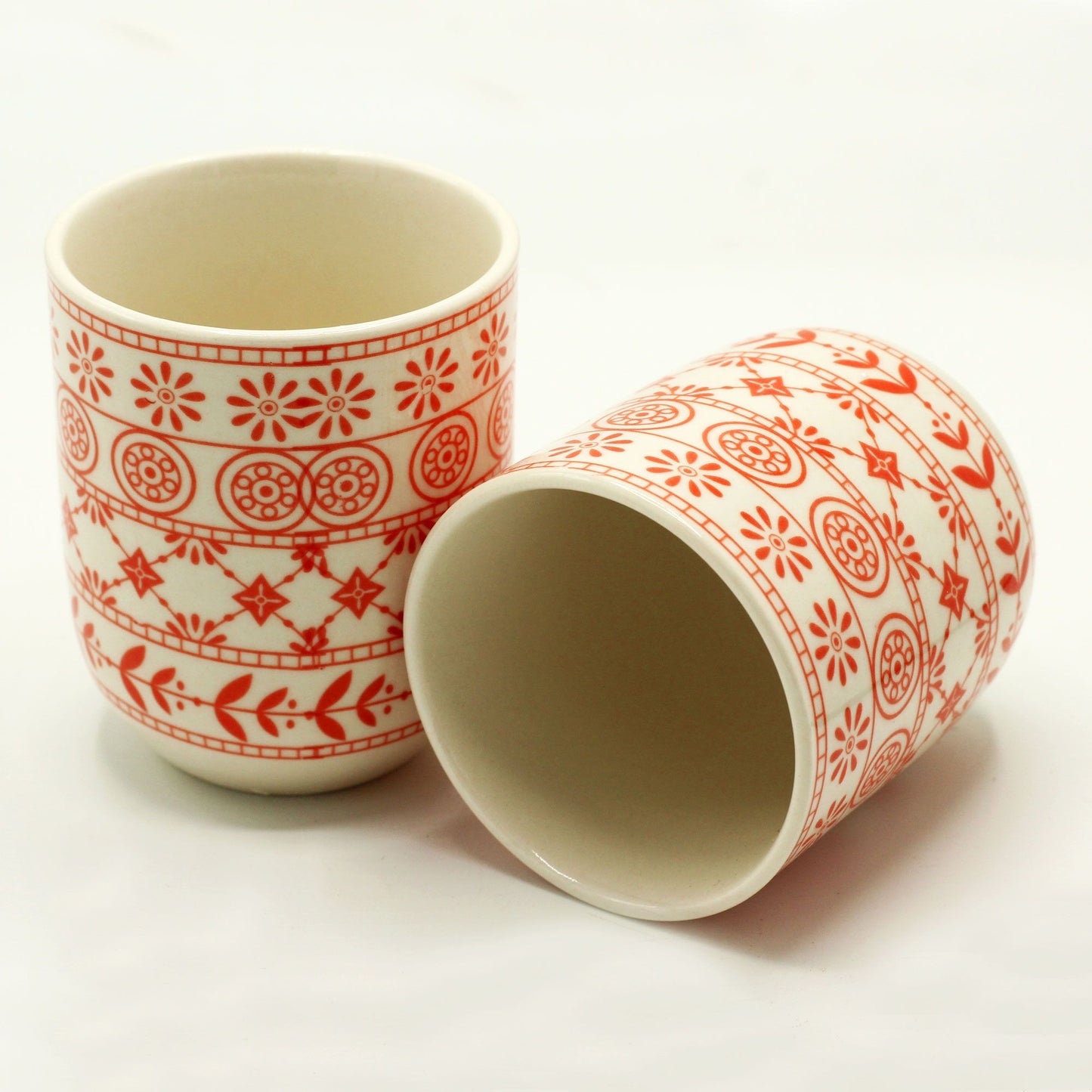 Two terracotta-colored ceramic tea cups with a detailed relief geometric pattern.