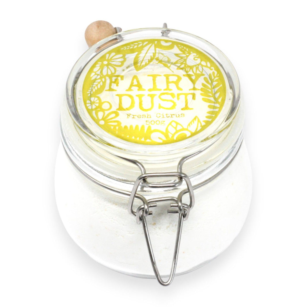 A glass apothecary jar containing 500g of bright yellow citrus-scented bath fizz and a traditional wooden serving scoop.