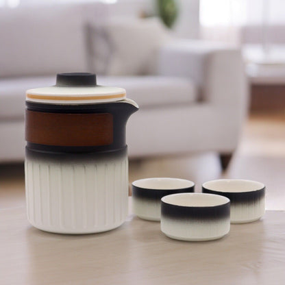 A premium travel tea set in a circular grey carrying case, featuring a modern matte-black ceramic teapot and matching cups.