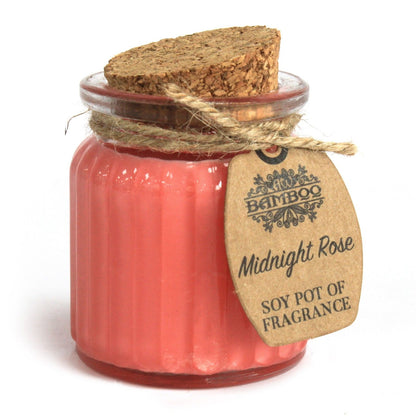 A small glass jar with a natural cork stopper containing deep pink scented soy wax and a rustic hanging tag.