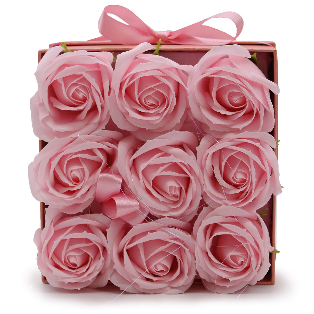 An elegant square gift box containing 9 realistic pink soap rose flowers for a luxury bath soak.