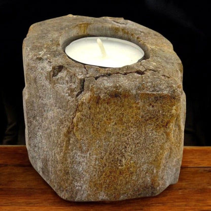 A short, sturdy candle holder carved from a single piece of petrified wood, featuring a hole for a tealight or small candle.