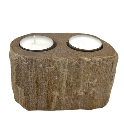 A heavy, polished double candle holder made from natural petrified wood with two holes for tealight candles.