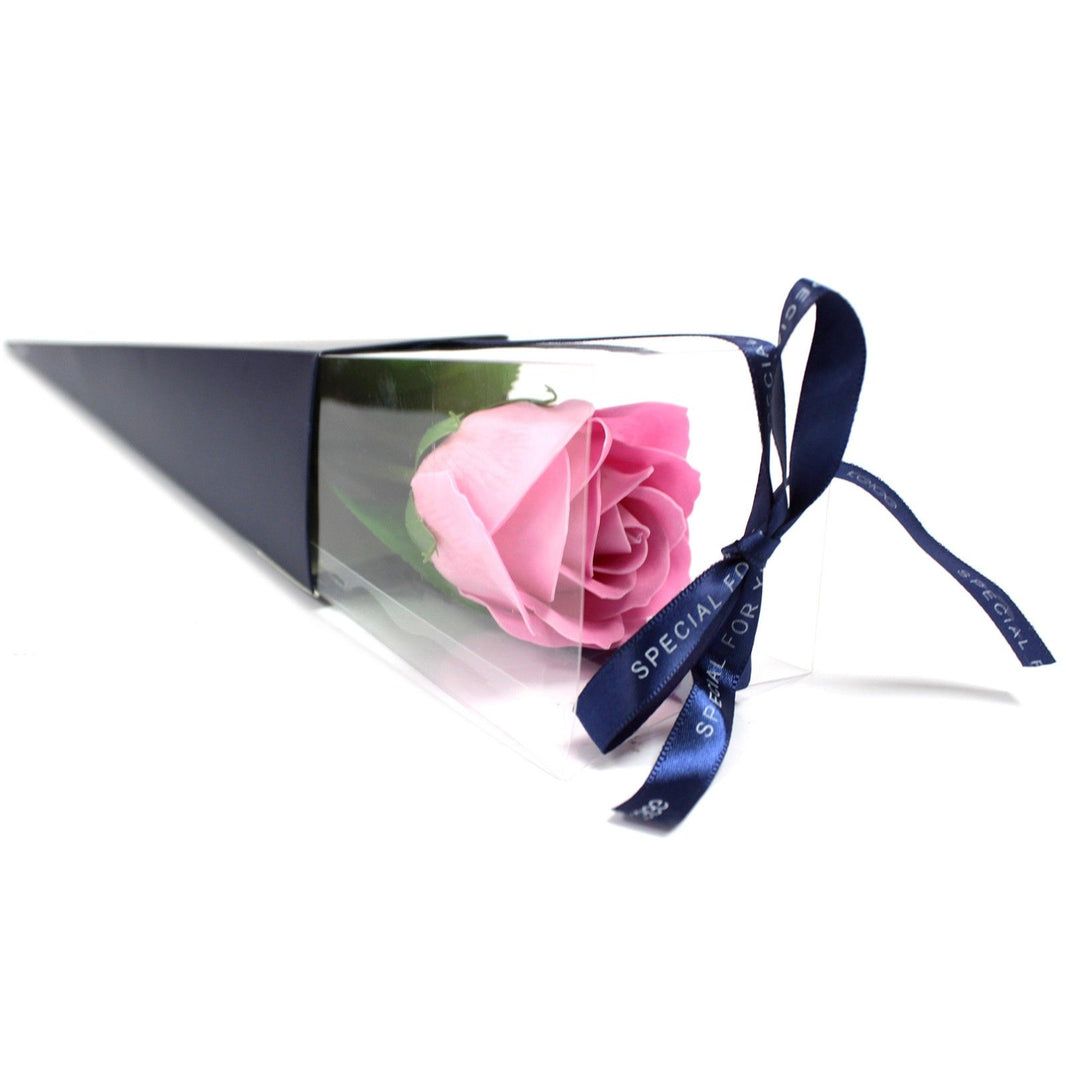 A single pink soap flower rose presented in a sleek, transparent triangular gift box with a decorative ribbon.