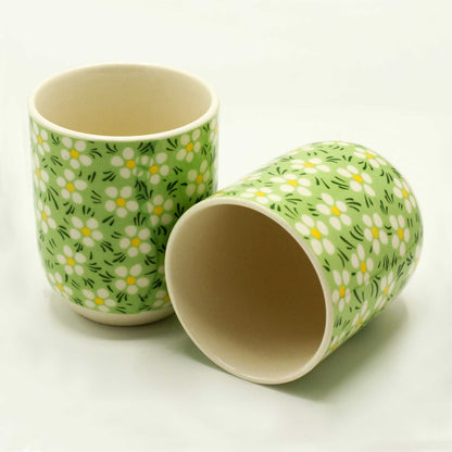 Two white ceramic tea cups with light green rims and white daisy flower patterns for herbal tea.
