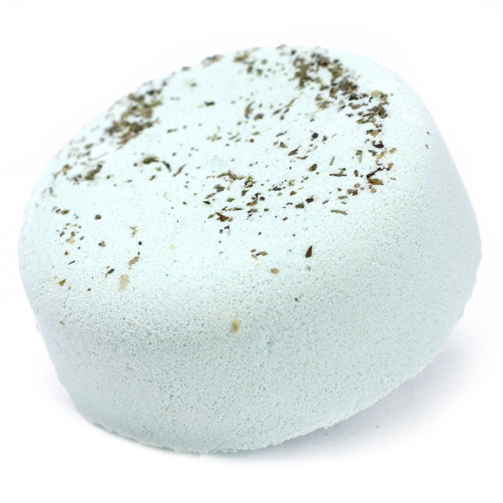 A light-colored, speckled bath bomb topped with a delicate scattering of dried botanical ingredients.