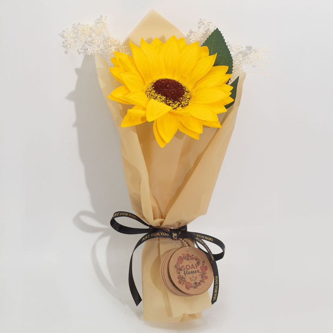 A single, large, realistic soap sunflower with bright yellow petals, presented in decorative gift packaging.