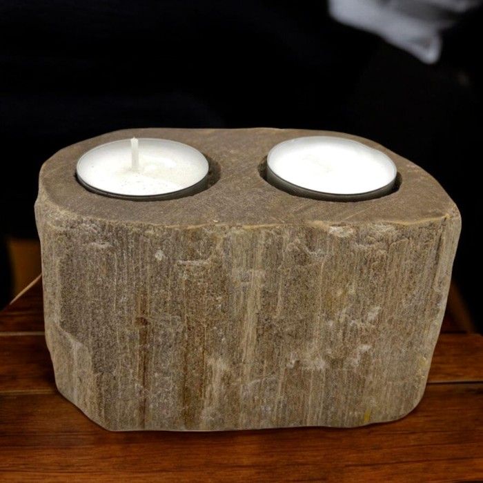 A heavy, polished double candle holder made from natural petrified wood with two holes for tealight candles.