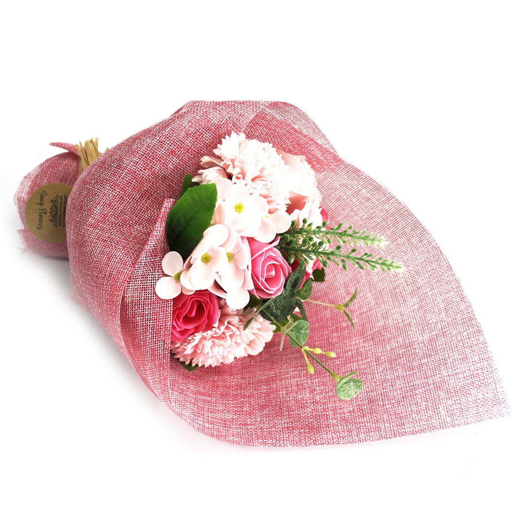 A standing arrangement of various pink soap flowers wrapped in decorative pink paper and ribbons.